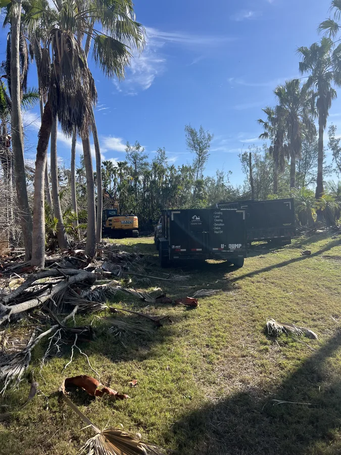 Lethermon branded dump trailer and excavator clearing vegetation on residential lot in Bradenton FL